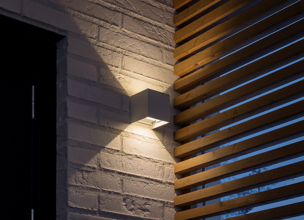 Lampada da parete FUNK con parete di mattoni bianchi.